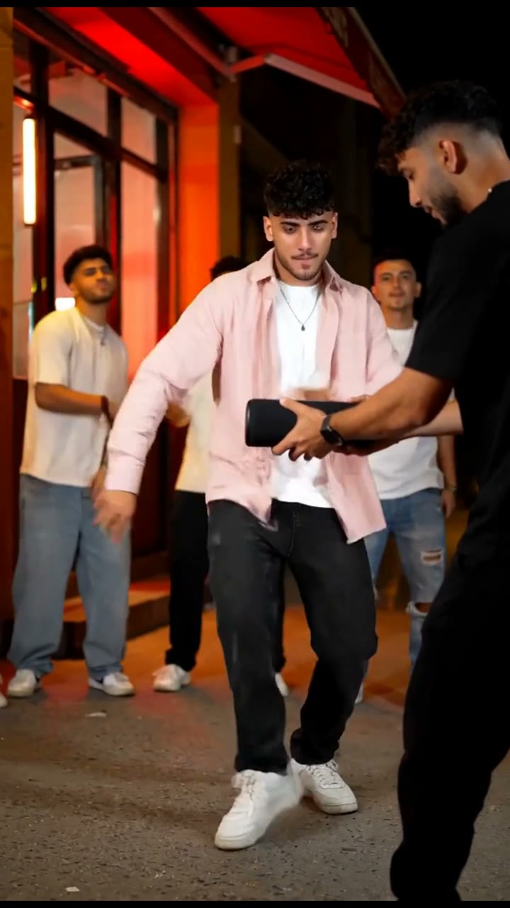 Original fictional street freestyler in a pale pink overshirt beside a friend holding a portable speaker